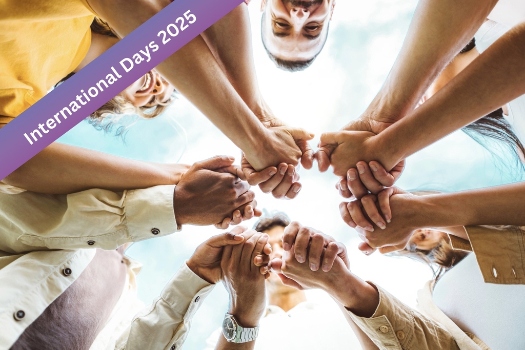 Mehrere Menschen halten sich die Hände in einem Kreis, "International Days 2025".