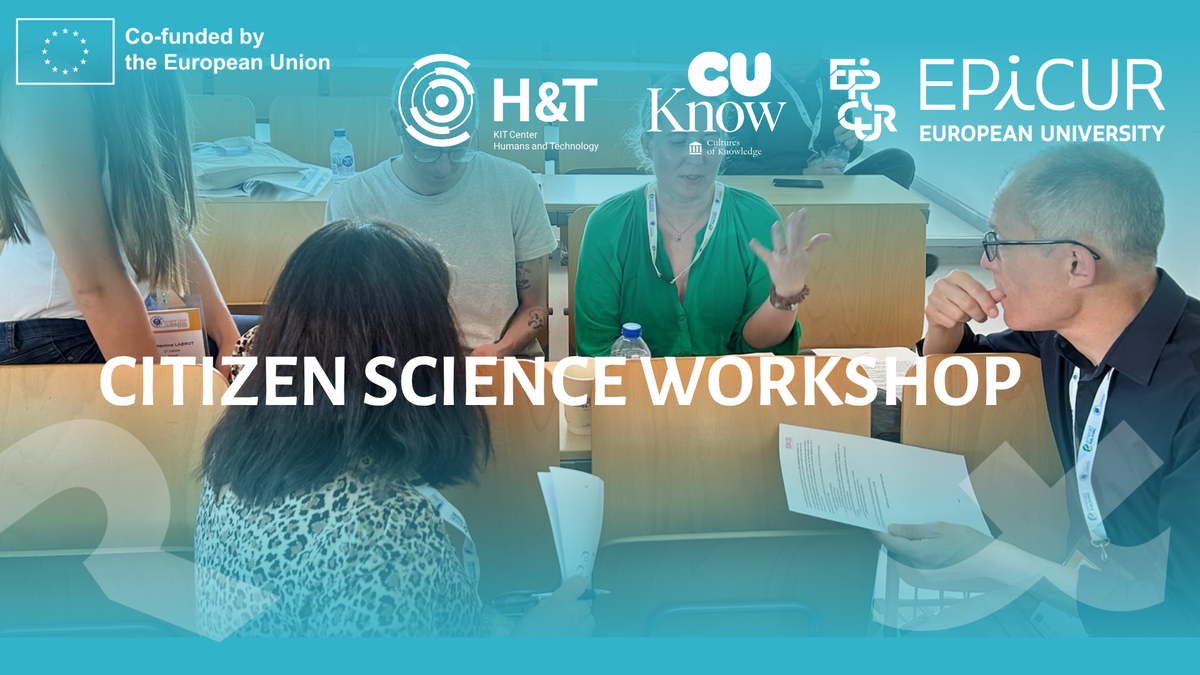 Outdoor information booth with people reading posters in front of a historic building.