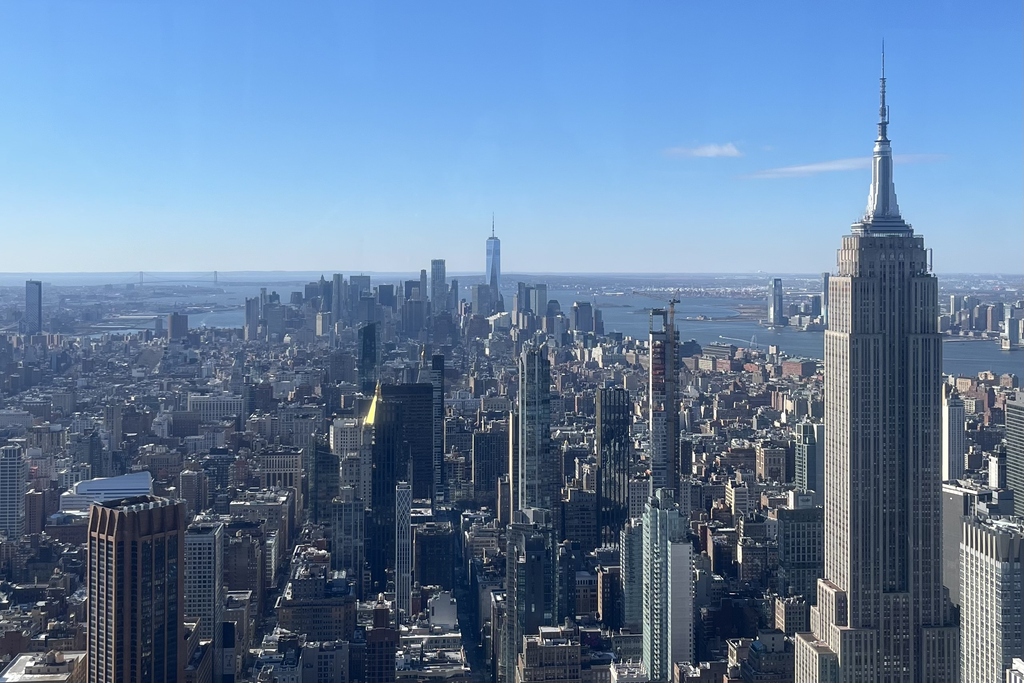 Blick über die Skyline von New York City mit Wolkenkratzern und blauem Himmel.