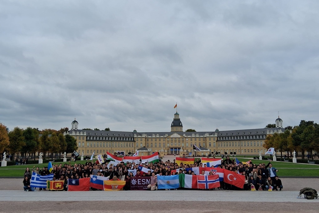 Großes internationales Studenten-Event vor Schloss Karlsruhe mit verschiedenen Nationalflaggen.