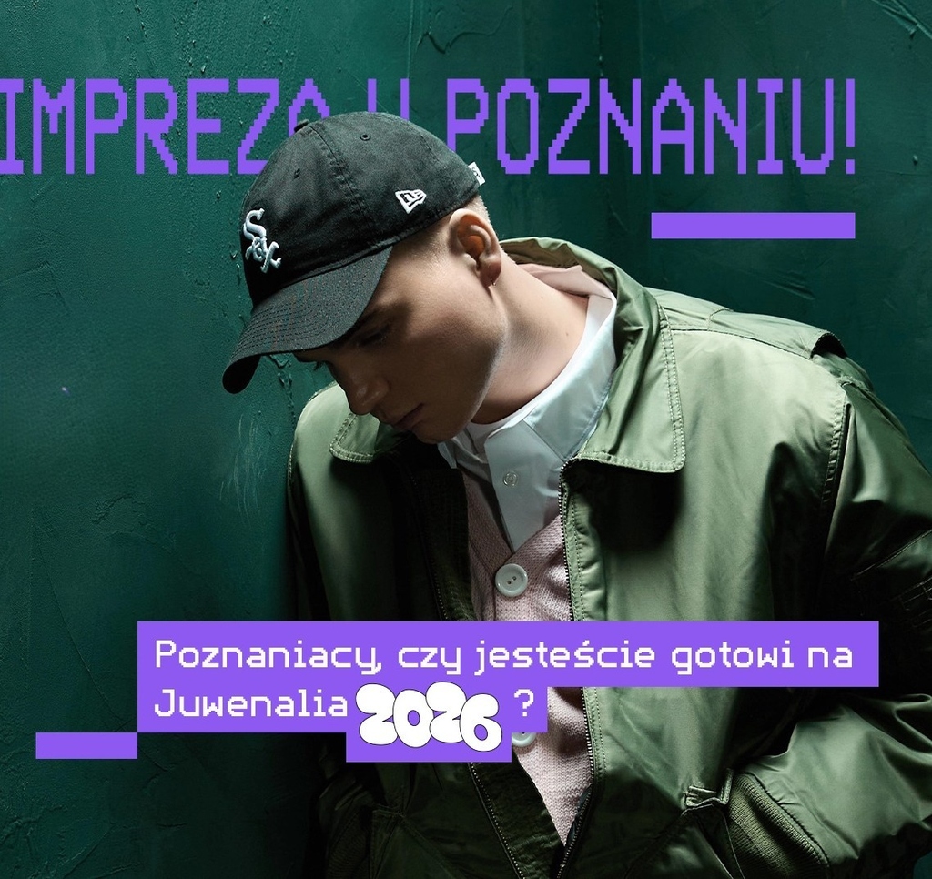 A person wearing a green jacket and cap against a teal wall with purple Polish text and graphics.